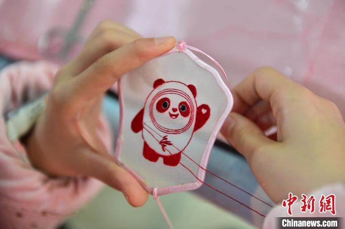 圖為一名小學(xué)生正在繡制2022年北京冬奧會(huì)吉祥物“冰墩墩”形象?！∮髟屏?攝