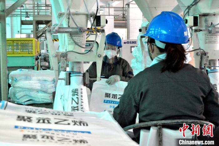 工人在生產(chǎn)線上包裝聚苯乙烯產(chǎn)品?！×趾霔v 攝