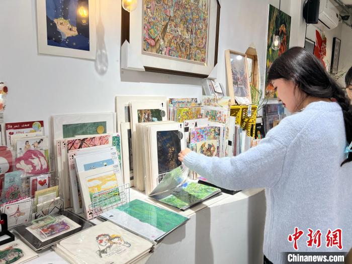 圖為藝術(shù)品商店內(nèi)，顧客挑選插畫作品?！＄婌?攝