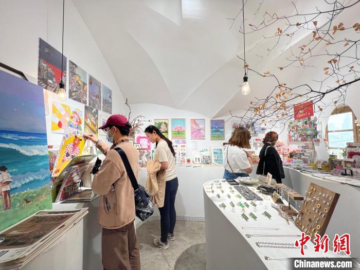 圖為藝術(shù)品商店內(nèi)，顧客挑選插畫作品?！＄婌?攝