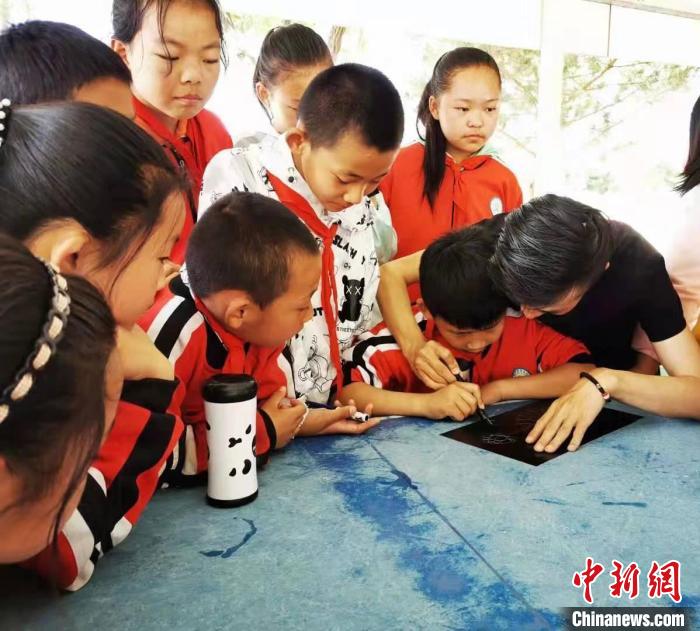 圖為朱增平(右一)教學(xué)生創(chuàng)作鍥金畫。(資料圖) 受訪者供圖