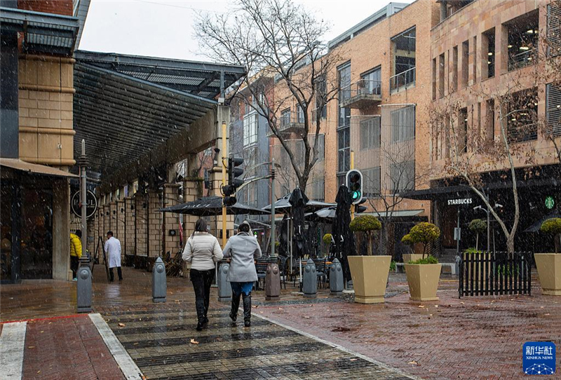 7月10日，在南非約翰內(nèi)斯堡一處商業(yè)區(qū)，人們在雪中行走。新華社記者 張譽東 攝