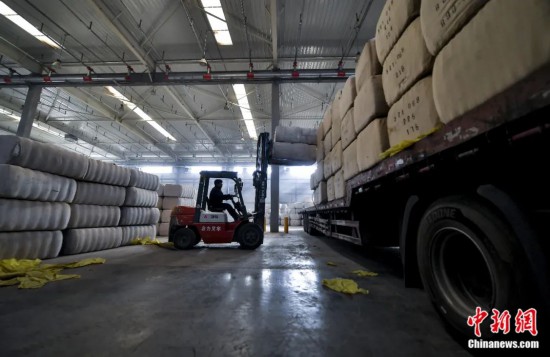 新疆喀什綜合保稅區(qū)，喀什啟路國(guó)際貿(mào)易有限公司的倉(cāng)庫(kù)內(nèi)，工人正在裝載從塔吉克斯坦和烏茲別克斯坦進(jìn)口的棉花。劉新攝
