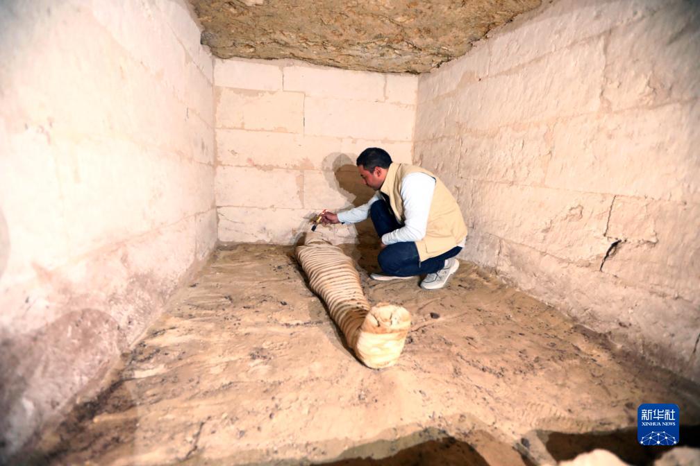 10月15日，在埃及明亞省考古現(xiàn)場(chǎng)，考古人員清理一座石鑿墓中的木乃伊。新華社發(fā)（艾哈邁德·戈馬攝）