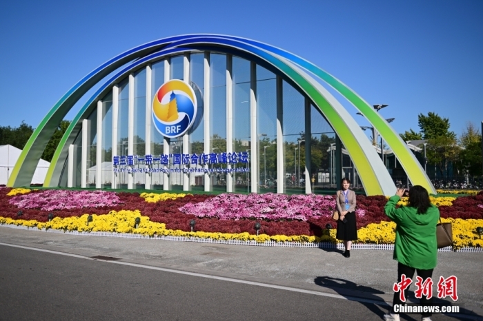 10月15日，北京，工作人員在國家會議中心外的第三屆“一帶一路”國際合作高峰論壇景觀布置前拍照留念。當日，位于國家會議中心的第三屆“一帶一路”國際合作高峰論壇新聞中心啟動試運行。據(jù)悉，第三屆“一帶一路”國際合作高峰論壇將于10月17日至18日在北京舉行。<a target='_blank' href='/'><p  align=