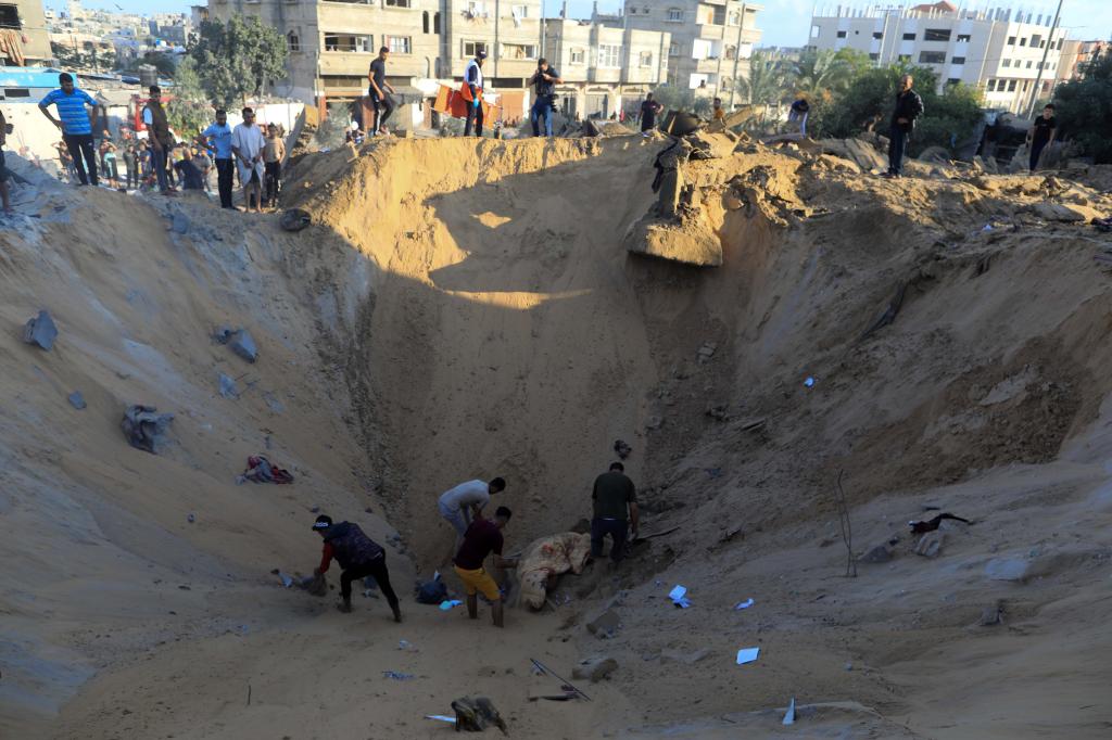 10月16日，在加沙地帶南部城市汗尤尼斯，人們在遭以色列襲擊后的建筑廢墟中救援傷者。 新華社發(fā)（亞西爾·庫迪 攝）