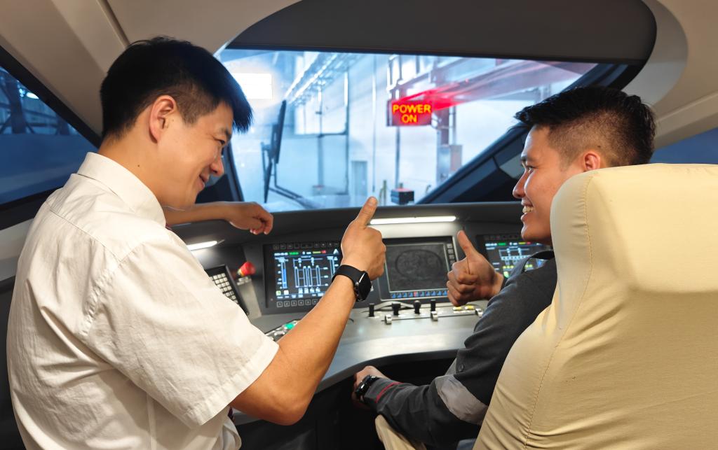 8月25日，在印度尼西亞萬隆的雅萬高鐵德卡魯爾動車所內(nèi)，中國師傅穆振（左）在向印尼火車司機塞蒂亞萬講解動車組出庫前的上電作業(yè)。