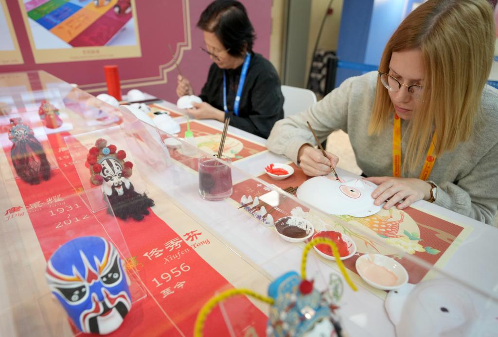 10月16日，在第三屆“一帶一路”國際合作高峰論壇新聞中心，來自比利時的記者（右）體驗畫京劇臉譜。新華社記者 王毓國 攝