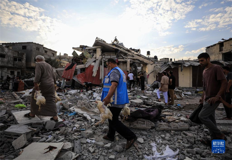 10月27日，在加沙地帶南部城市汗尤尼斯，人們經(jīng)過以軍襲擊后的房屋廢墟。