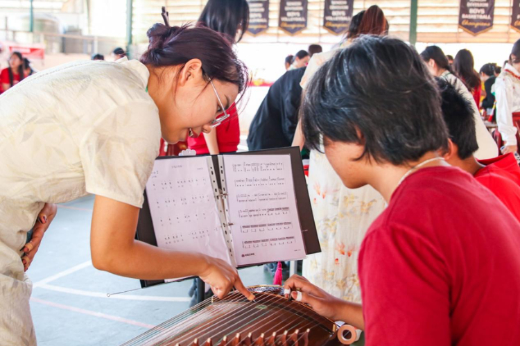 志愿者教師指導(dǎo)學(xué)生彈奏古箏。活動主辦方供圖