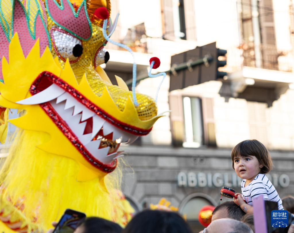 2月18日，在意大利羅馬，一名小朋友在彩妝巡游上觀看舞龍。新華社記者 李京 攝