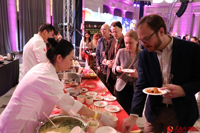 當(dāng)?shù)貢r(shí)間3月7日晚，華盛頓聯(lián)合車站廣場(chǎng)舉行駐美使團(tuán)“使館主廚挑戰(zhàn)賽”。圖為當(dāng)?shù)孛癖娫谥袊古_(tái)前體驗(yàn)中國美食。人民網(wǎng)記者 李志偉攝