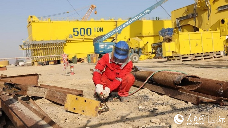 工人正在龍門吊吊裝現(xiàn)場切割金屬件。人民網(wǎng)記者管克江攝