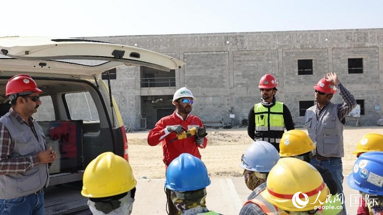 穆薩瓦爾(圖中紅衣人）現(xiàn)場演示工具操作規(guī)范。人民網(wǎng)記者 管克江攝