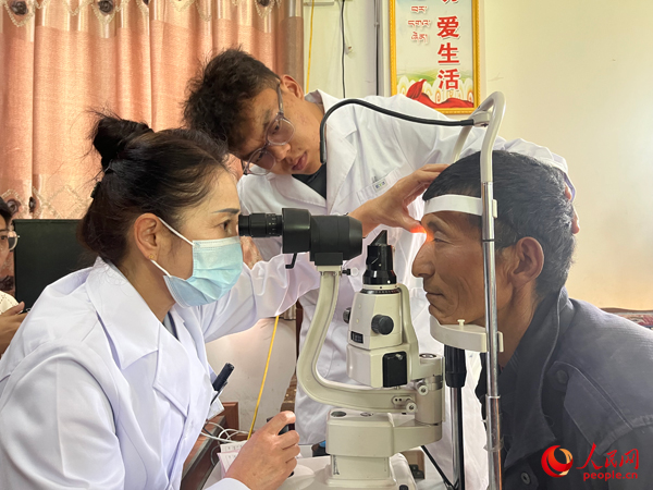 王紅英（左）和團隊成員為達熱村村民檢查眼睛。人民網(wǎng)記者 杜燕飛攝