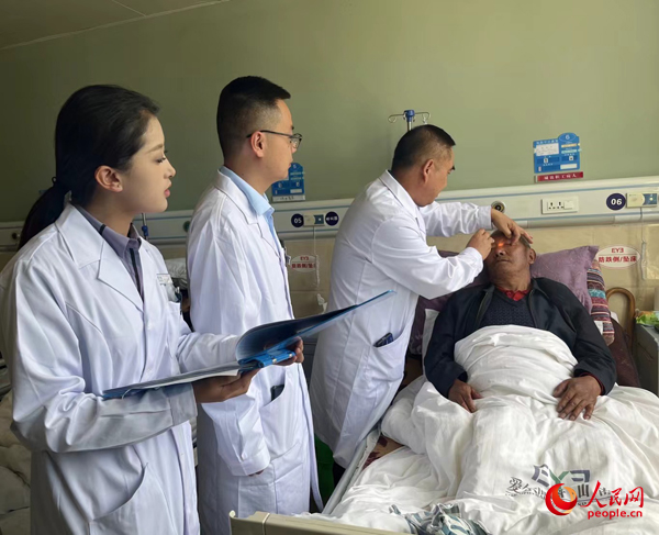 董光明（左三）帶領醫(yī)生對患者進行術前檢查。人民網(wǎng)記者 杜燕飛攝