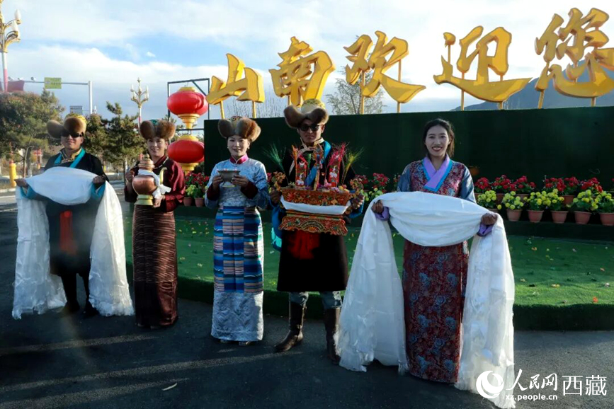 扎西曲登社區(qū)的居民在“山南歡迎您”標(biāo)志前，手持潔白哈達(dá)和切瑪，列隊(duì)迎接來自區(qū)內(nèi)外的游客，用最隆重的禮儀開啟一場沉浸式藏歷新年民俗體驗(yàn)之旅。人民網(wǎng)記者 吳雨仁攝
