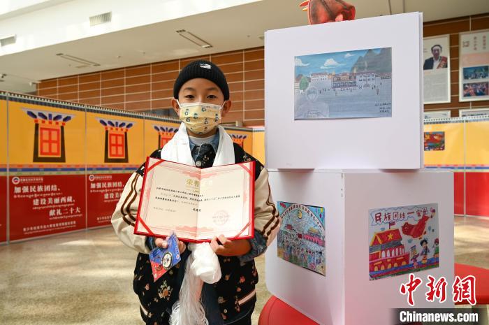 圖為一名獲獎學(xué)生與自己的繪畫作品合影?！≮w朗 攝