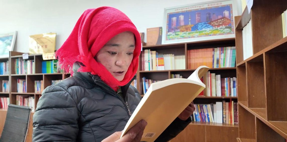 一名婦女正在認(rèn)真閱讀書籍。申扎縣融媒體中心供圖