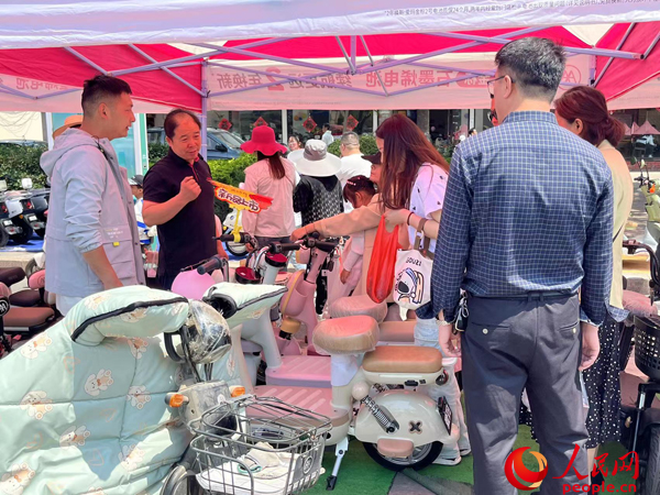 某電動自行車品牌工作人員向消費者介紹以舊換新相關(guān)情況。人民網(wǎng)記者 杜燕飛攝
