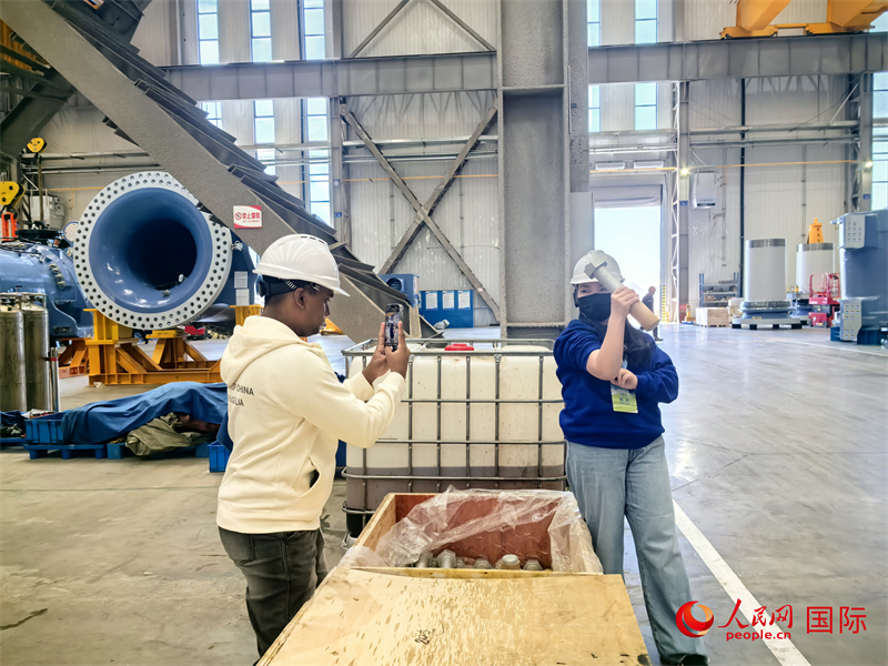 外媒記者掂量廠房?jī)?nèi)的巨型螺栓。人民網(wǎng) 楊春燕攝