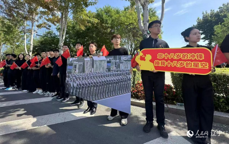 沈陽市人民廣場上，大學(xué)生們手持閱兵的圖片，告慰英烈。人民網(wǎng)記者 周頌雪攝