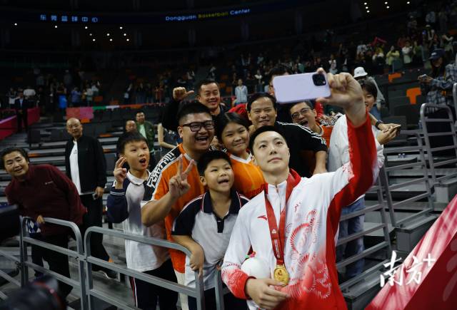 11月12日，十五運(yùn)會男籃成年組決賽，廣東隊(duì)獲得冠軍后，胡明軒與球迷們合影留念。張由瓊 攝