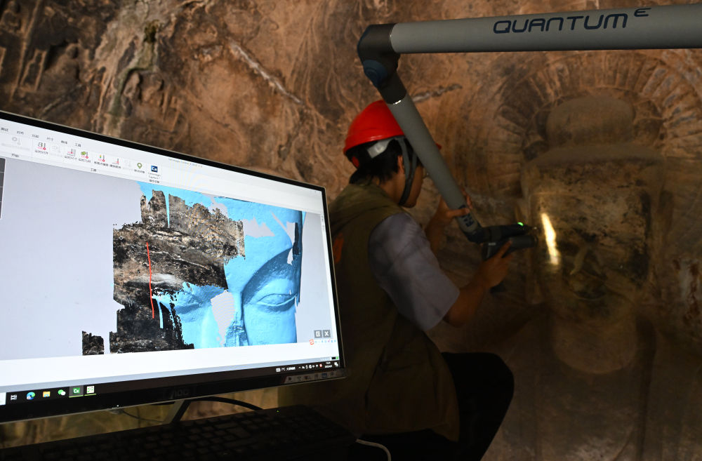 2025年4月9日，武漢大學(xué)文化遺產(chǎn)智能計(jì)算實(shí)驗(yàn)室團(tuán)隊(duì)成員在魏字洞使用關(guān)節(jié)臂掃描儀對(duì)佛像進(jìn)行數(shù)字化掃描。圖片來(lái)源新華社