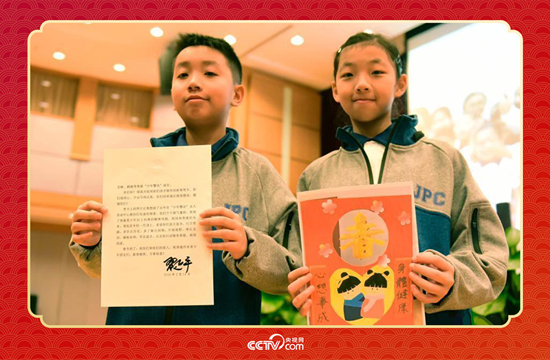 圖為香港“少年警訊”成員郭宏晞（左）展示習(xí)主席回信、羅顥凝（右）展示送給習(xí)主席的賀卡并合影。