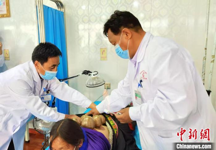 圖為看照加手把手帶徒弟加老(左一)進(jìn)行拔罐療法。　張婧 攝