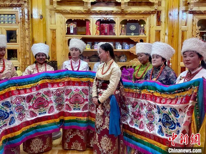 圖為女性展示村民自發(fā)繡制的“百米五彩哈達(dá)”?！±钣穹?攝
