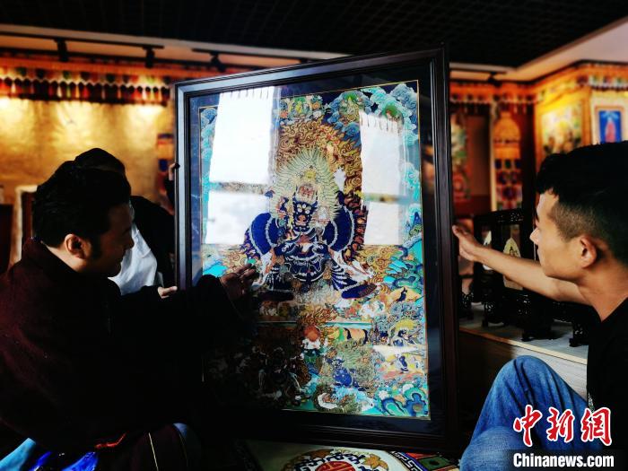 圖為久美尖措(左)與徒弟們展示唐卡作品?！?zhí)砀?攝