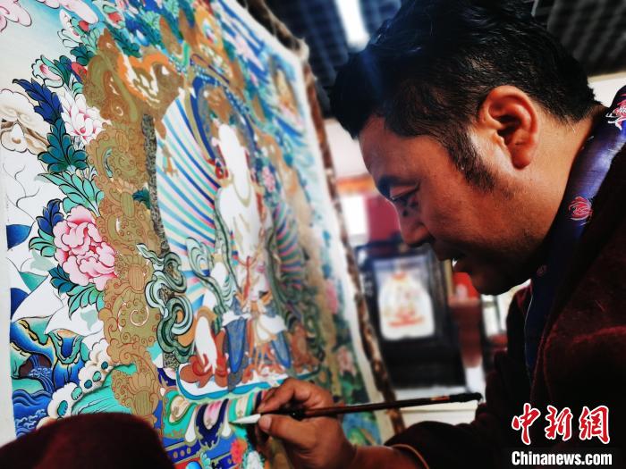 圖為久美尖措創(chuàng)作唐卡?！?zhí)砀?攝