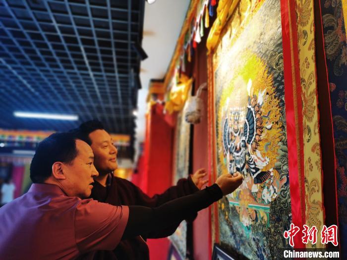 圖為久美尖措展示唐卡作品?！?zhí)砀?攝