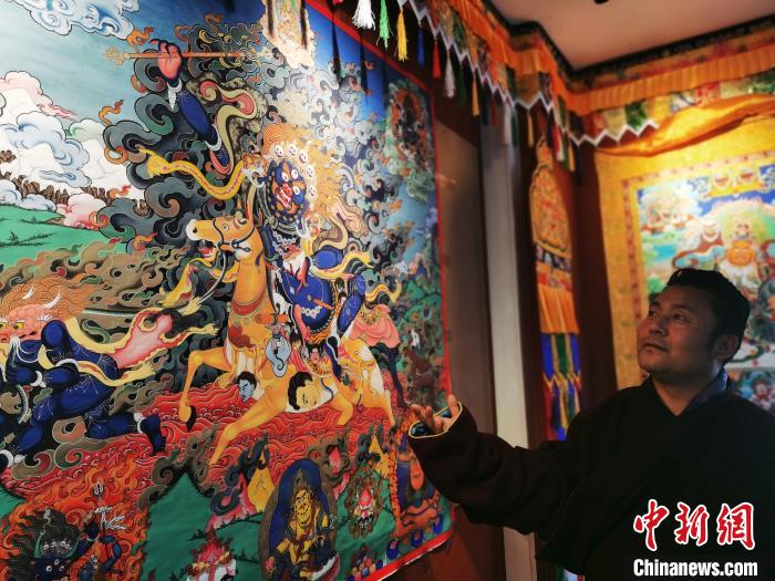圖為久美尖措展示唐卡作品?！?zhí)砀?攝