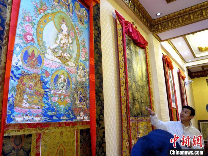 圖為完德尖措展示熱貢龍樹畫苑內(nèi)的唐卡?！?zhí)砀?攝