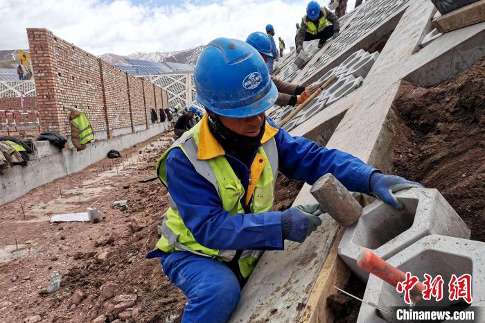 圖為光伏發(fā)電項(xiàng)目施工區(qū)工人在護(hù)坡鋪設(shè)空心磚?！±铍h 攝