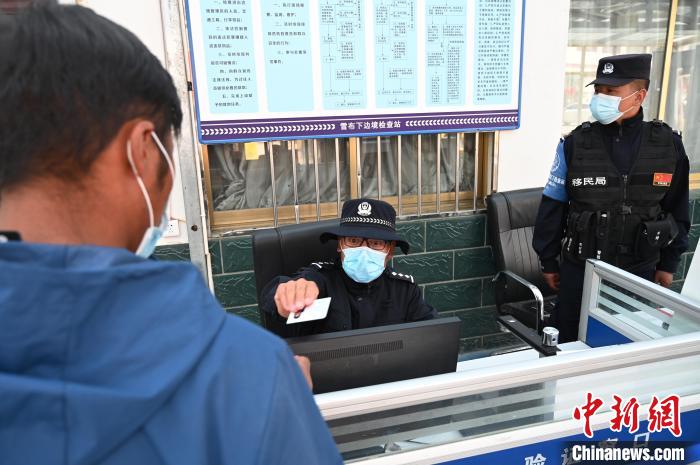 圖為移民管理警察登記完身份信息后將證件歸還給行人?！≮w朗 攝