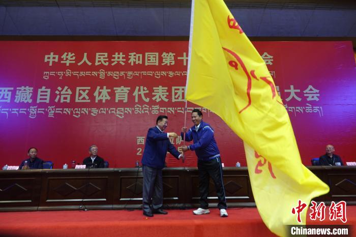 西藏自治區(qū)副主席甲熱·洛桑丹增授代表團(tuán)團(tuán)旗，西藏自治區(qū)體育局局長尼瑪次仁接旗?！∪轿木?攝