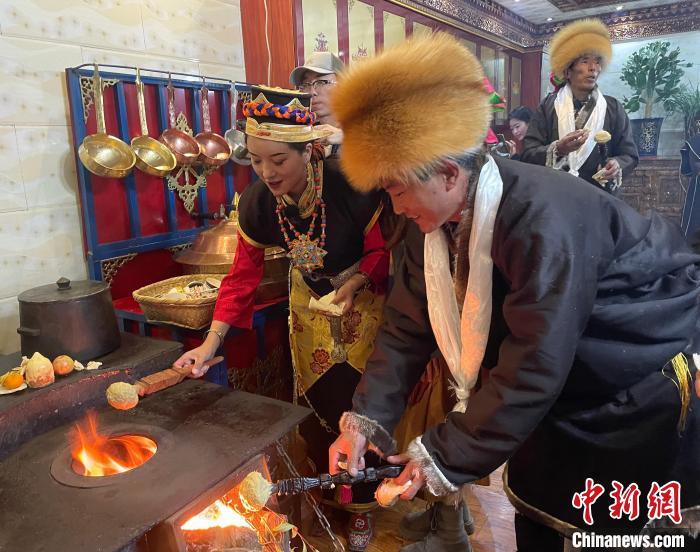 圖為人們在火上烤節(jié)日美食“結(jié)達”?！∪轿木?攝