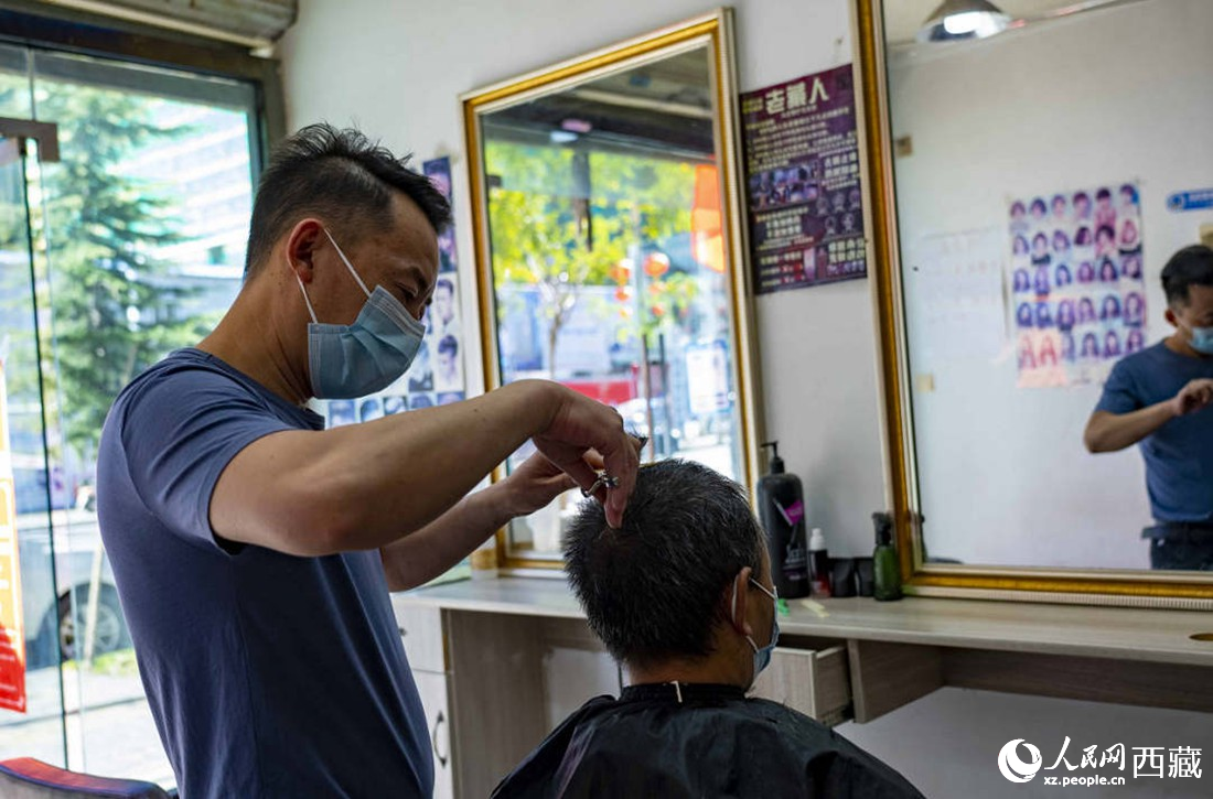 理發(fā)店老板為顧客理發(fā)。次仁羅布 攝