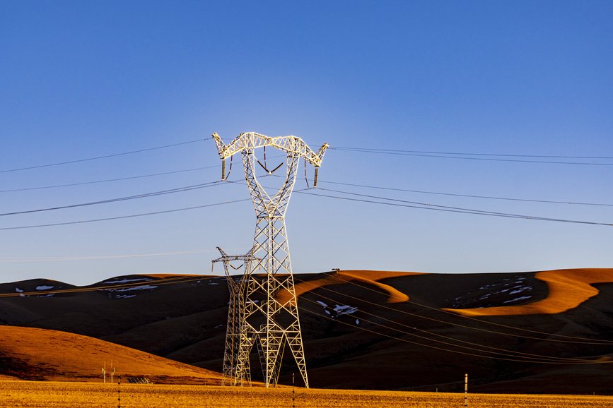 阿里地區(qū)的曠野上，電力鐵塔在夕陽(yáng)下熠熠生輝。