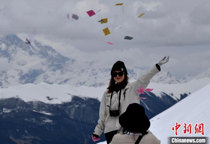 圖為5月14日，游客在西藏林芝色季拉山觀景臺拋灑“隆達”(風(fēng)馬旗，藏族民眾的一種祈福方式)?！±盍?攝