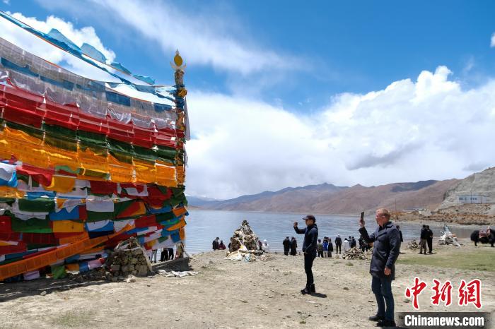 進藏參訪嘉賓在羊湖畔拍攝經幡?！〗w波 攝