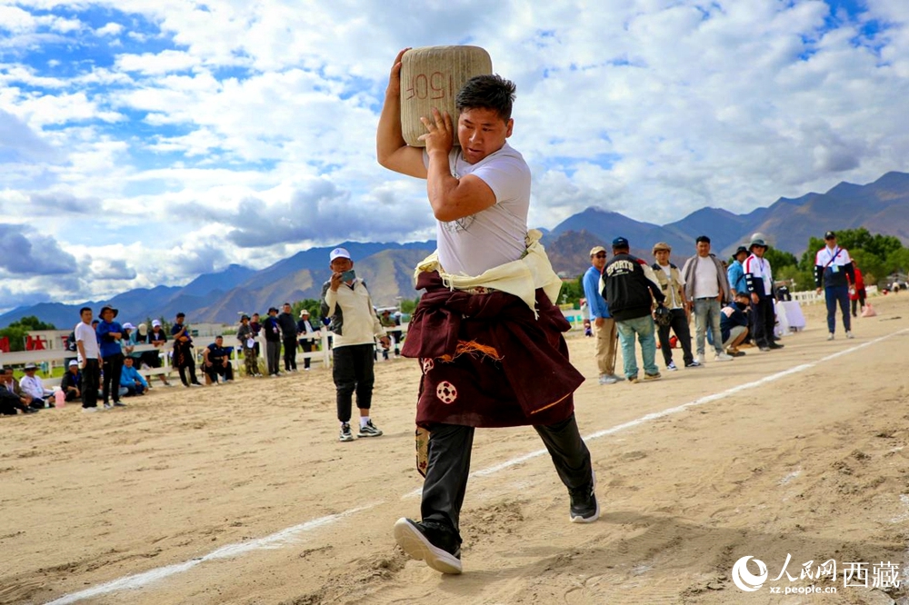 來自拉薩市當(dāng)雄縣的牧民選手將一塊150斤重的石頭扛在肩上飛奔。
