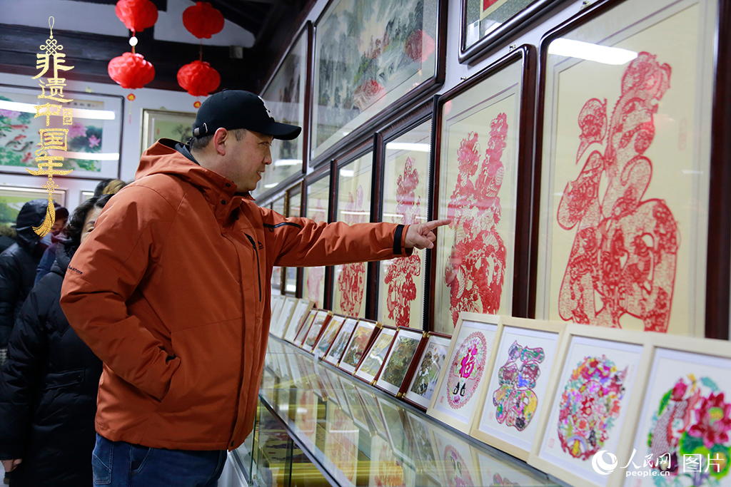 2025年1月23日，游客在天津楊柳青古鎮(zhèn)欣賞傳統(tǒng)剪紙作品，感受指尖上的古老藝術。人民網記者 崔新耀攝