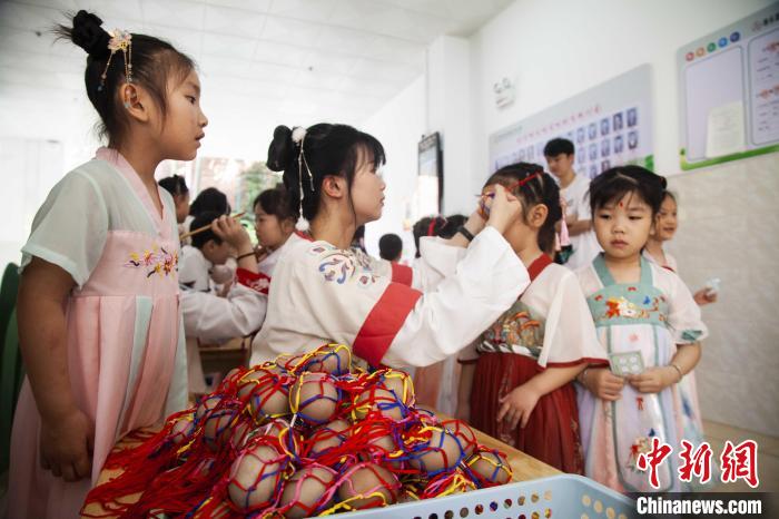 圖為幼兒園的老師們穿上漢服為小朋友們戴上彩蛋，寓意著幸福安康?！《^生 攝