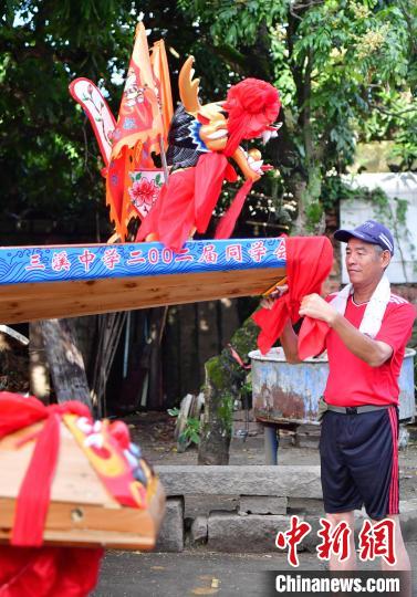 圖為5月29日，長樂江田鎮(zhèn)村民為即將入水的新龍舟系紅布。　張斌 攝